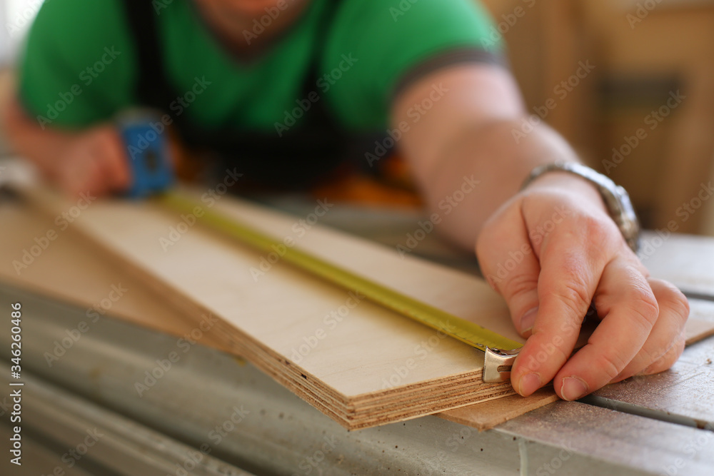 Arms of worker measuring wooden bar closeup