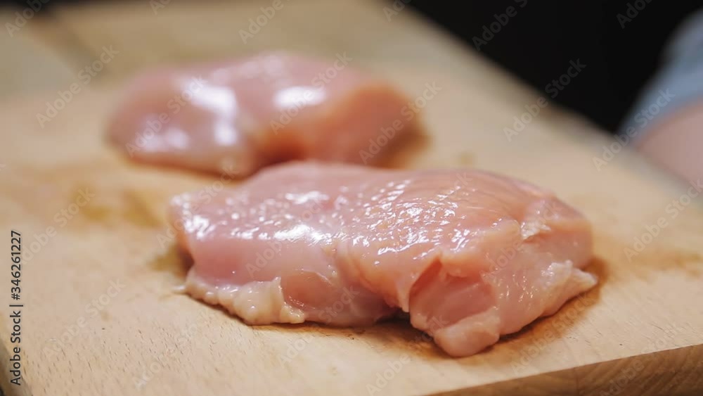 A female hand beats the chicken with a metal hammer. A female hand beats the chicken with a metal hammer.