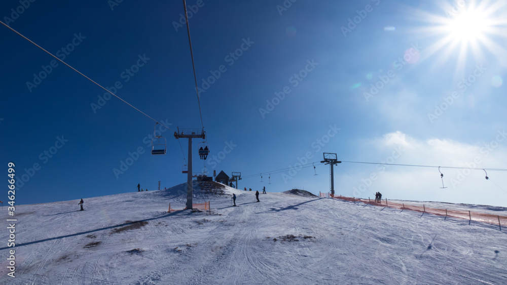 Top of mountain against blue sky at sunny day in the Carpathians. Ski lift is lifting people to top of mountain. Top of mountain against blue sky at sunny day in the Carpathians. Ski lift is lifting people to top of mountain.