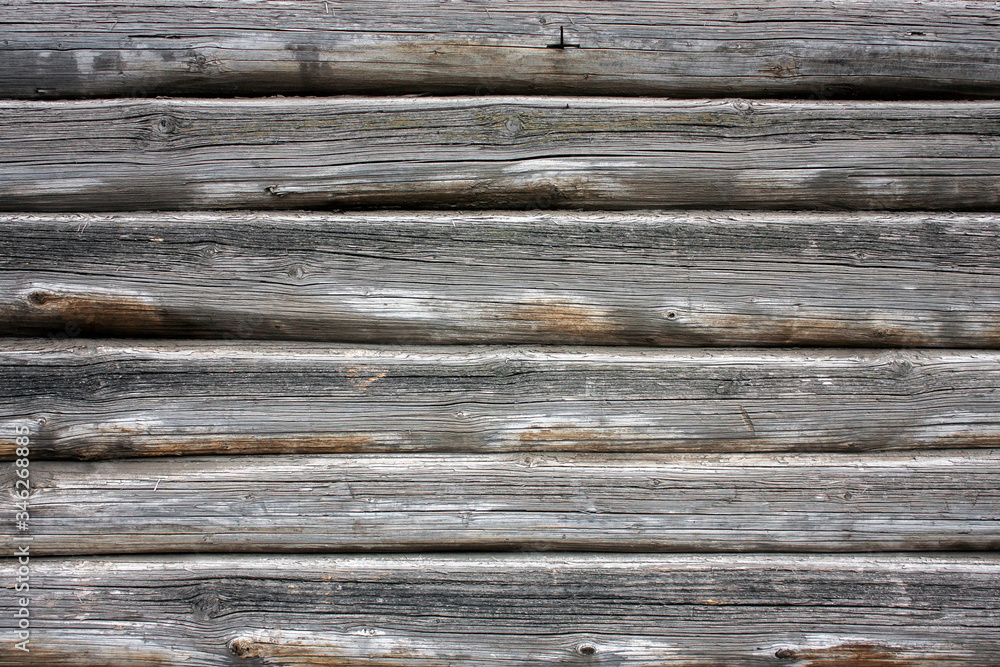 A fragment of the wall of the log house close-up. Natural wood, rough texture.The wall of an old wooden house of logs. A fragment of the wall of the log house close-up. Natural wood, rough texture.The wall of an old wooden house of logs.