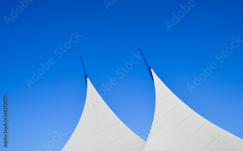 Top of a white structure in the design of sails isolated against a blue sky. No people. Space for copy