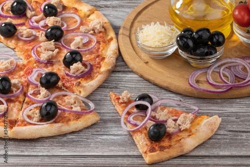Pizza with tuna, red onion and olives on wooden background