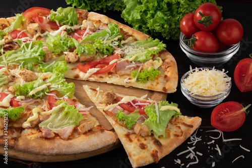 Pizza with bacon, chicken and lettuce on wooden background