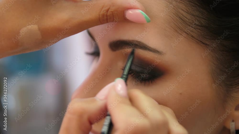 Draw the brow line with a makeup pencil. Make-up artist doing makeup for the young girl, close-up. Draw the brow line with a makeup pencil. Make-up artist doing makeup for the young girl, close-up.