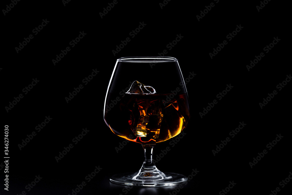 a glass of whisky with ice on black background a glass of whisky with ice on black background