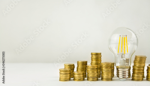 Business concept. Lamp with coins on a light background. Concept of birth of an idea. Business finance concept. Recovery and business growth. Copy space. Banner.