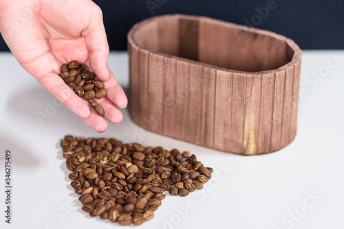 Coffee beans spilling out of a hand on a table  forming the shape of a heart
