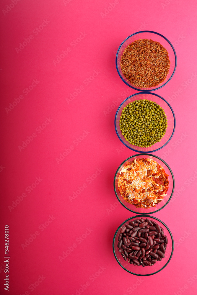 Glass jars with cereal mung bean, lentils, beans, brown rice on a pink background. Glass jars with cereal mung bean, lentils, beans, brown rice on a pink background.