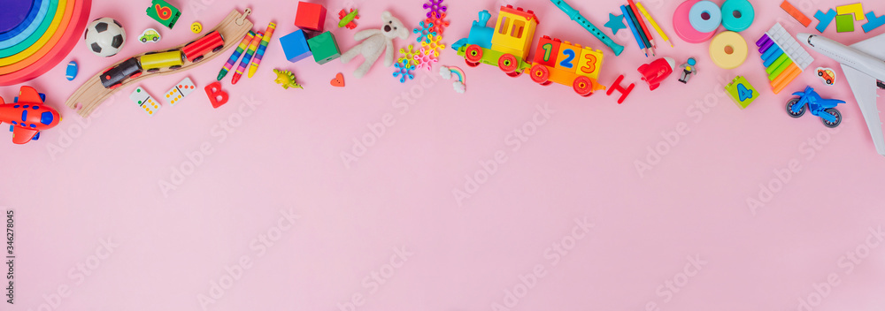 Frame of plastic and wooden kids toys on pink background