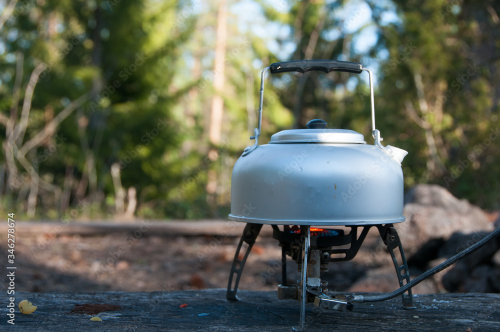 Aluminum kettle on gas camping stove. Camping kitchen. Picnic. Cooking at nature. Making tea. Boil water. Aluminum teapot on gas stove. 