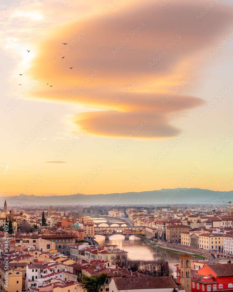the famous bridge in Florence Ponte vecchio during the GOLDEN hour after sunset, the lights of the buildings reflect on river arno .Panoramic view from michelangelo square 