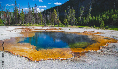 Dark green blue orange brown basin in Yellowstone national park Wyoming United States. World famous landmark background with hot springs and geysers nature view of pool with microorganisms and steam 