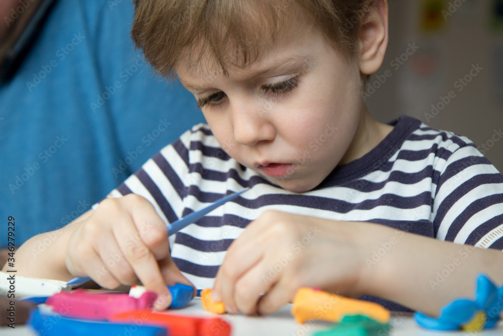 Portrait of a child who enthusiastically sculpts from plasticine. Development of fine motor skills with parents. Portrait of a child who enthusiastically sculpts from plasticine. Development of fine motor skills with parents.