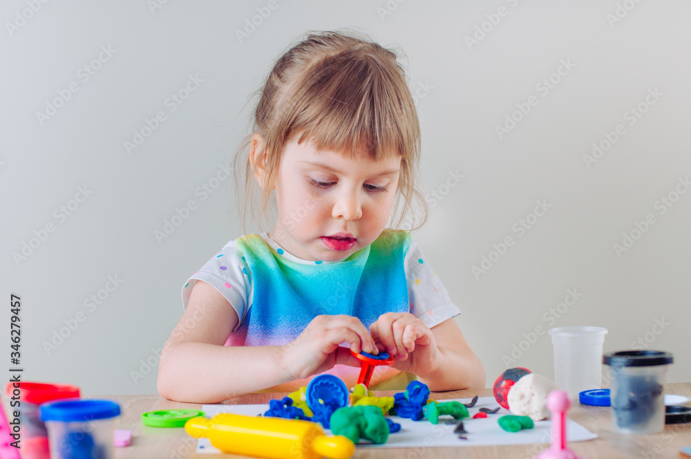 Little four years old girl molding from colorful childs play clay on the table Little four years old girl molding from colorful childs play clay on the table