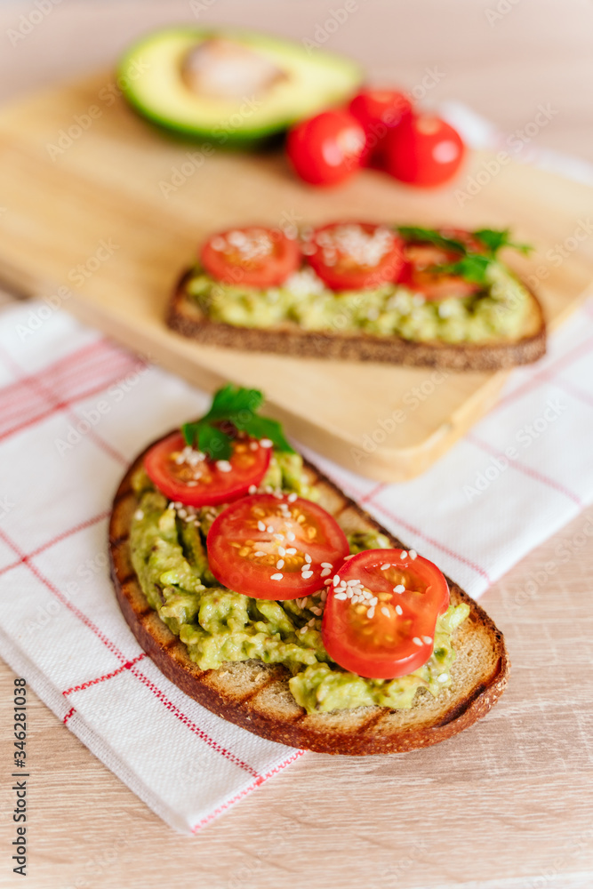 toasted bread with avocado paste and fresh tomato. Avocado mixed with lemon juice is spread on bread.  health food concept, vegan, vegetarian