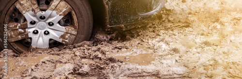 The car got stuck on a dirt road in the mud. Wheel of a car stuck in the mud on the road. © Yauhen