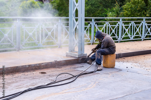 Worker with protective mask sandblasting of metal bridge photo