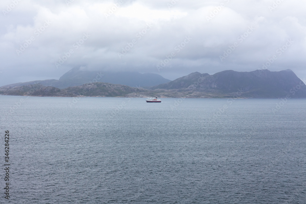 ship to visit fjords in Norway. A mystical fjord with dark clouds in Norway with mountains and fog hanging over the water ship to visit fjords in Norway. A mystical fjord with dark clouds in Norway with mountains and fog hanging over the water
