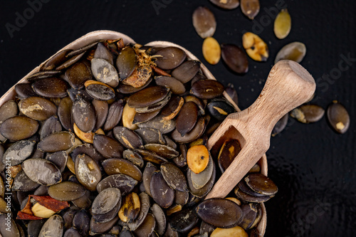 Dark pumpkin seeds in a container with a wooden container. Tasty seeds that contain a lot of good oil. photo