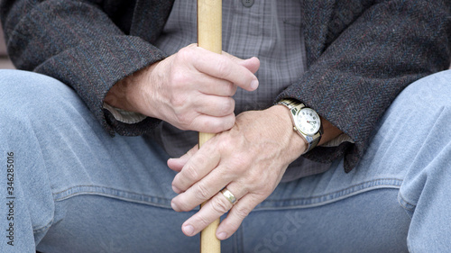 Elderly man holding cane as he sits on steps.