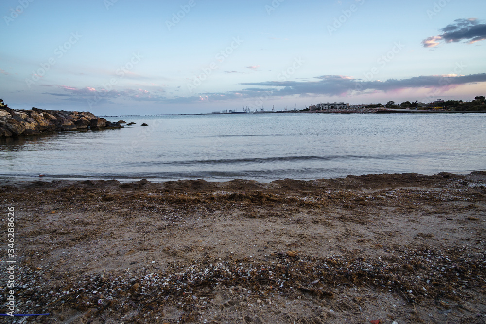 Fotografía Tomada en el espigón del Puerto de Sagunto. Se muestra un paisaje marinero en el cual aparece el espigón el mar y parte de puerto marítimo. 