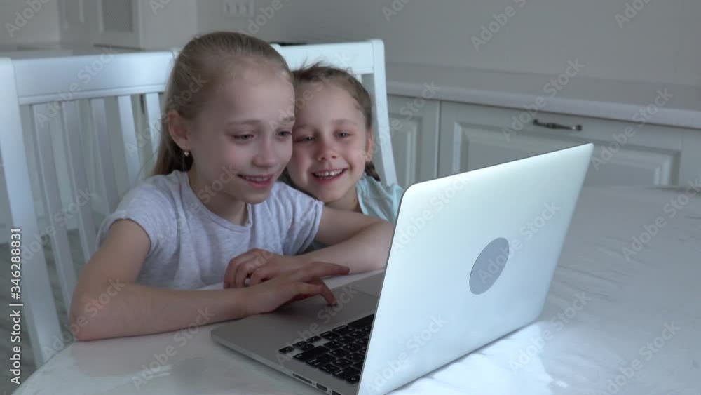 Pretty two kids using laptop studying online from home typing in internet smiling, social distance during quarantine, self-isolation, online education concept, home schooler Pretty two kids using laptop studying online from home typing in internet smiling, social distance during quarantine, self-isolation, online education concept, home schooler