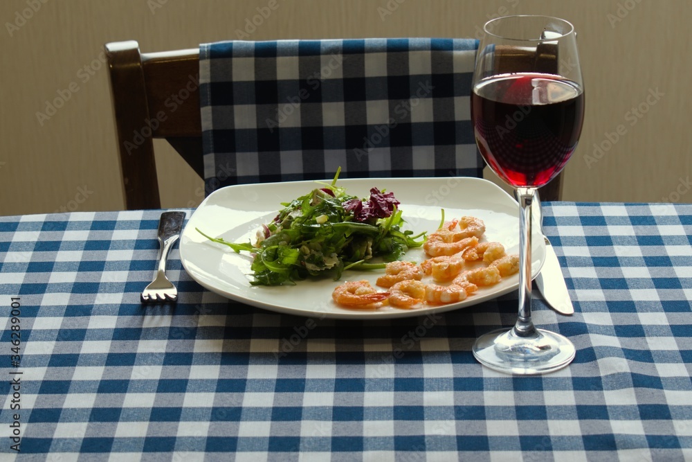 green salad with shrimp and wine on a table with a tablecloth
