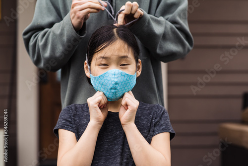Woman tying strings of mask for girl