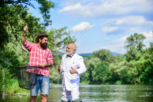 Catching and fishing concept. fly fish hobby of businessman. retirement fishery. retired dad and mature bearded son. happy fishermen friendship. Two male friends fishing together. Misty morning © be free