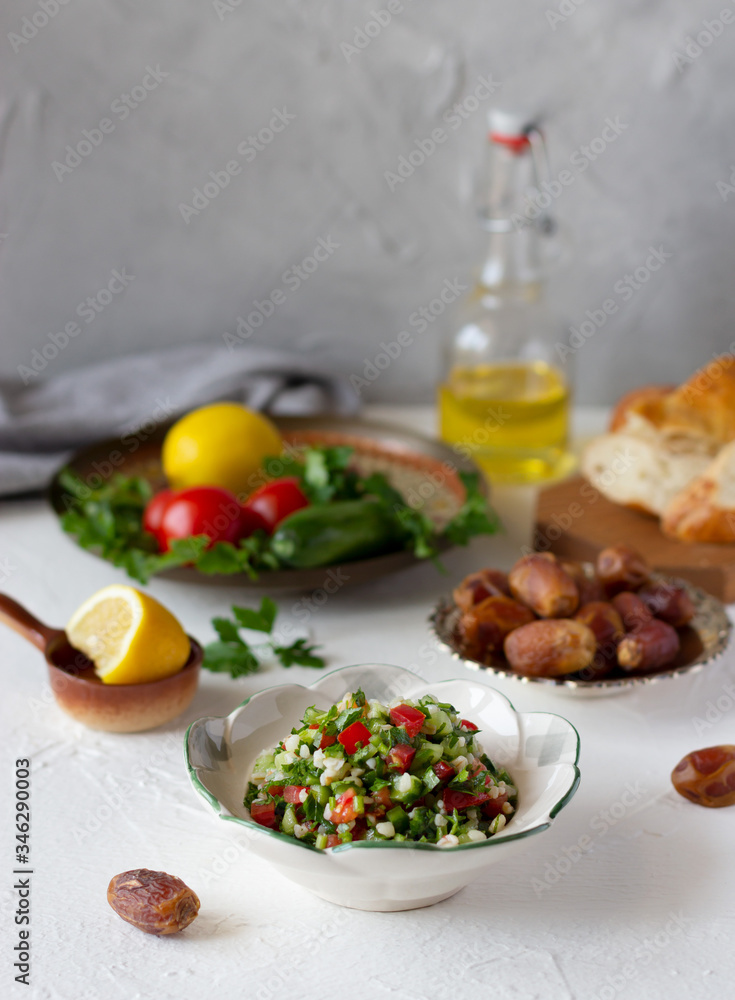 Iftar, evening meal during month of Ramadan. Tabbouleh salad, dates, fresh vegetables, bread on the table