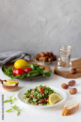 Iftar, evening meal during month of Ramadan. Tabbouleh salad, dates, glass of water and fresh vegetables on the table. Copy space