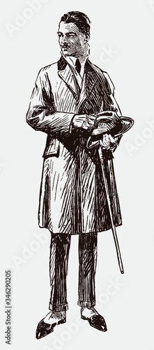 Man from the early 20th century wearing overcoat and gaiters and holding hat and walking stick