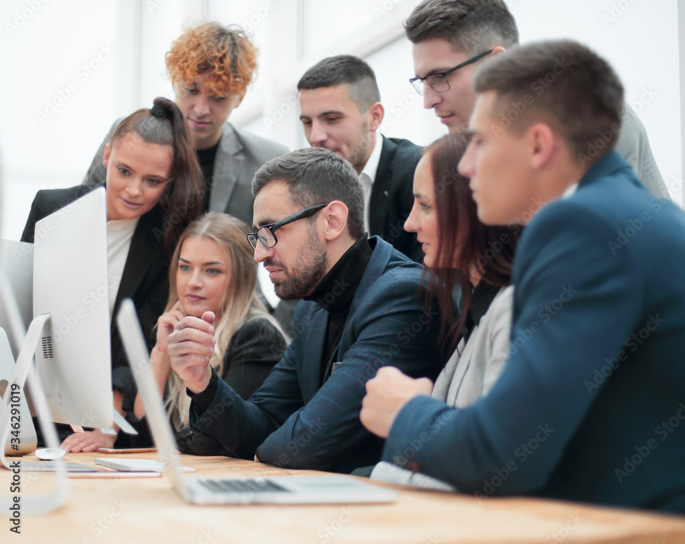 team of young employees looking together at a computer screen. team of young employees looking together at a computer screen.