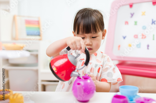 toddler girl prerend play preparing tea party at home