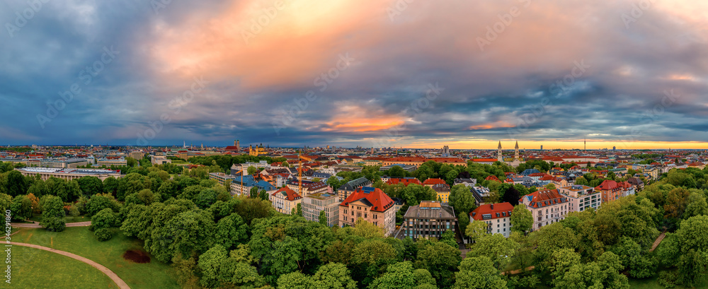 Obraz premium The wonderful view at Munich in bavaria from a drone, an panoramic aerial over a park, houses and the frauenkirche in the historical center of the bavarian capital at the early morning.