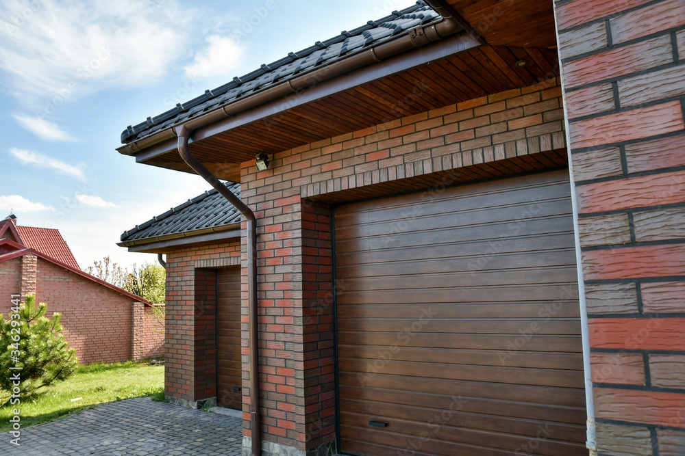 Fragment of two-car garage with pull-up doors on a sunny day. Fragment of two-car garage with pull-up doors on a sunny day.
