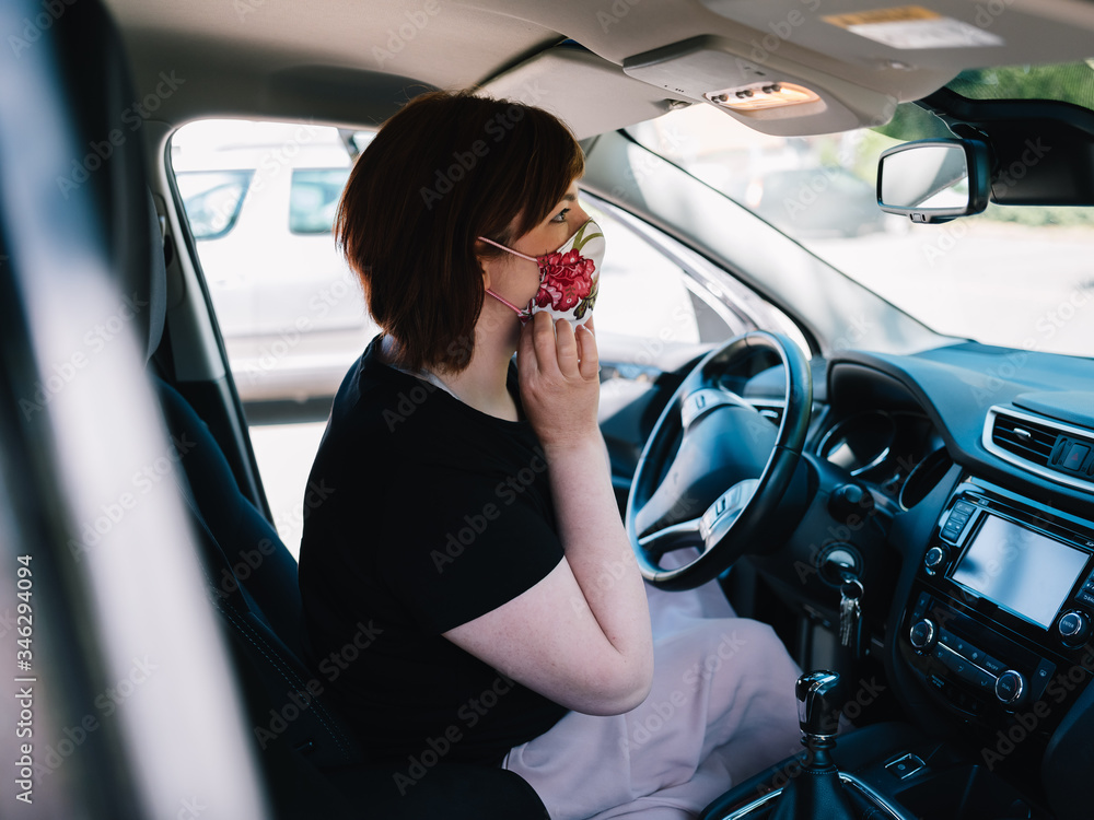 Frau mit Mundschutz im Auto auf dem Weg zur Arbeit