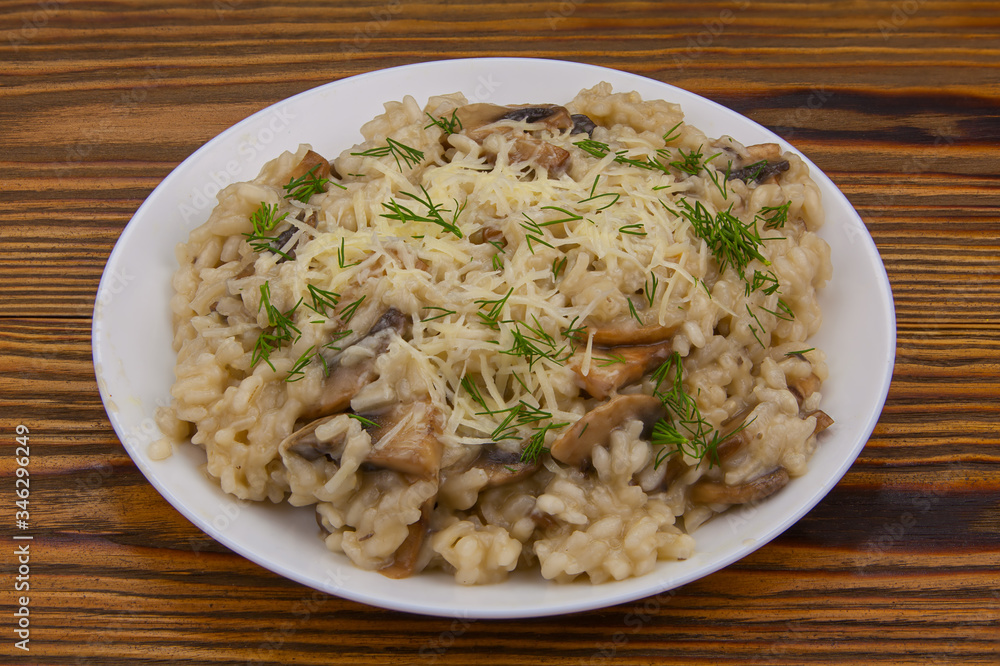 Tasty appetizing risotto on white plate on wooden table Tasty appetizing risotto on white plate on wooden table