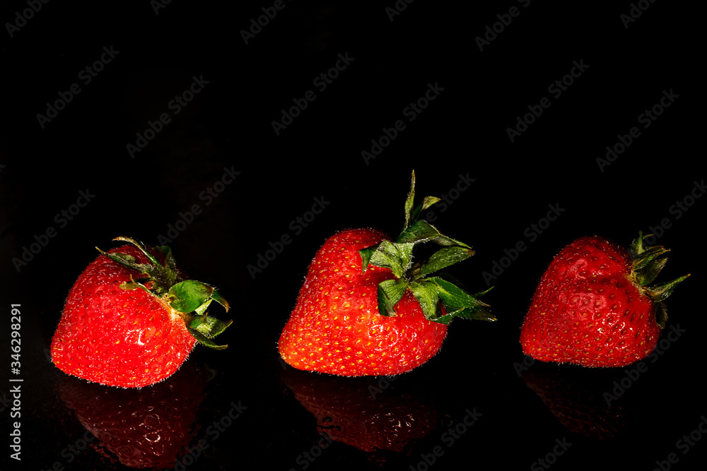 Three fresh strawberries on a black background with a reflection Three fresh strawberries on a black background with a reflection