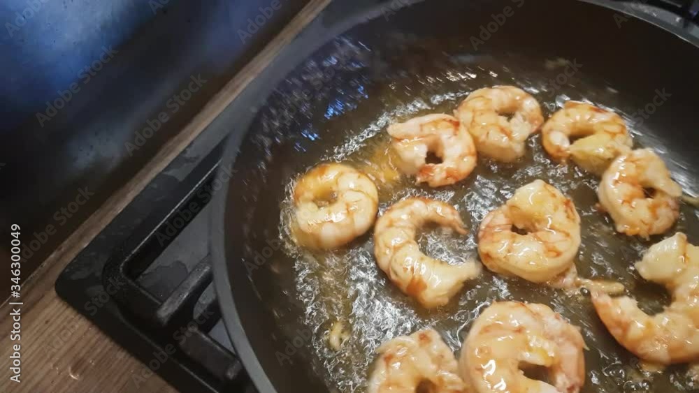 The cook roasts the prawns in a frying pan, turning them several times. The cook roasts the prawns in a frying pan, turning them several times.