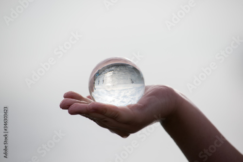a child's hand holds a glass ball against the background of the sea