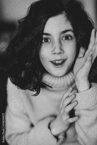 Close-up portrait of a charming European girl of 8 years old. She has beautiful wavy, loose hair. Black and white photo.
