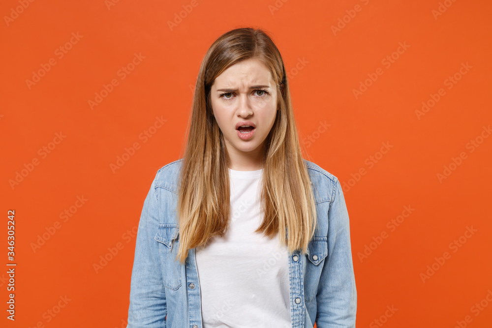 Perplexed shocked young woman girl in casual denim clothes posing isolated on orange wall background studio portrait. People sincere emotions lifestyle concept. Mock up copy space. Looking camera. Perplexed shocked young woman girl in casual denim clothes posing isolated on orange wall background studio portrait. People sincere emotions lifestyle concept. Mock up copy space. Looking camera.