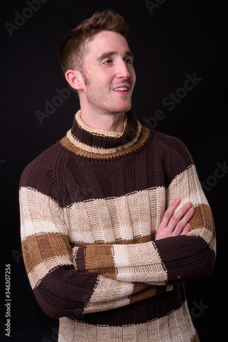 Happy young handsome man thinking with arms crossed ready for winter