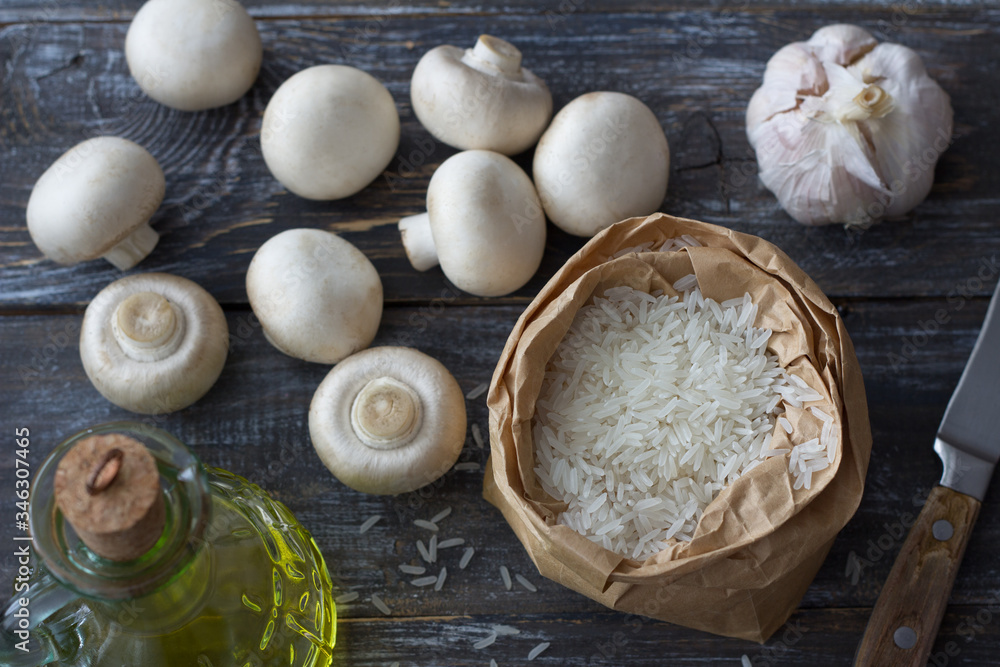 Fototapeta premium Ingredients for a delicious vegan dish. White basmati rice, garlic and champignons on a wooden table, top view, horizontal