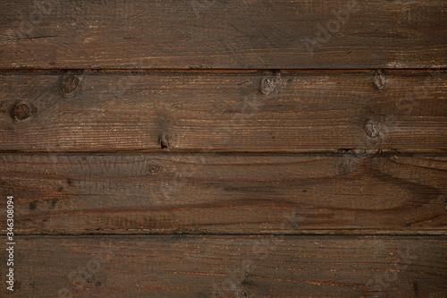 Dark brown surface of an old wooden floor, wall or table with cracks and knots. Dark rough weathered wood.