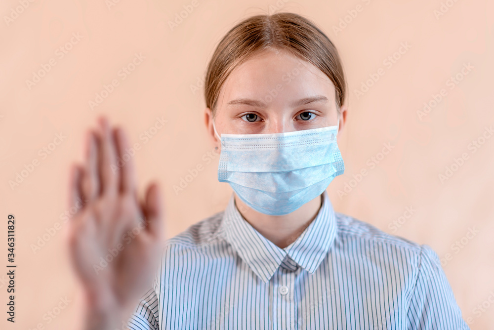 girl in protective medical mask covers her face, hand gesture stops attention and carefully virus. Flu infection is a disease and pandemic. Beige background. girl in protective medical mask covers her face, hand gesture stops attention and carefully virus. Flu infection is a disease and pandemic. Beige background.