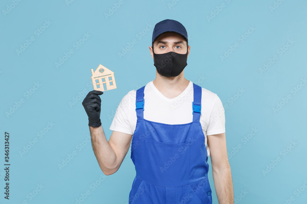 Delivery man in cap t-shirt coveralls uniform sterile face mask gloves isolated on blue background studio. Guy employee courier Service quarantine pandemic coronavirus virus covid-19 2019-ncov concept Delivery man in cap t-shirt coveralls uniform sterile face mask gloves isolated on blue background studio. Guy employee courier Service quarantine pandemic coronavirus virus covid-19 2019-ncov concept
