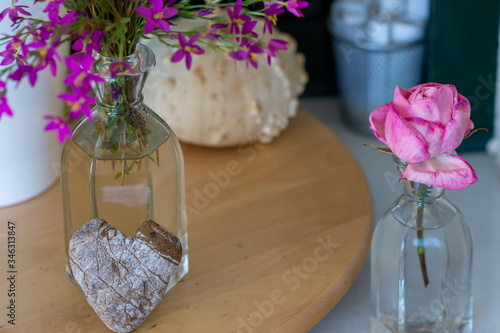 Interior decoration  home corner with a pink rose  a dried pumpkin  a glass vase with wild flowers and a heart-shaped stone
