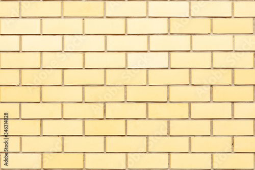 The natural background of the wall is made of yellow finishing bricks. Smooth brickwork of a modern building.